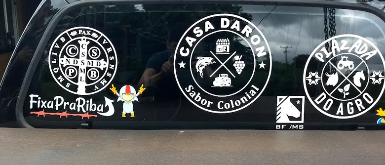 Adesivos de vidro da Casa Daron e da Pizza do Agro aplicados no vidro traseiro de um carro