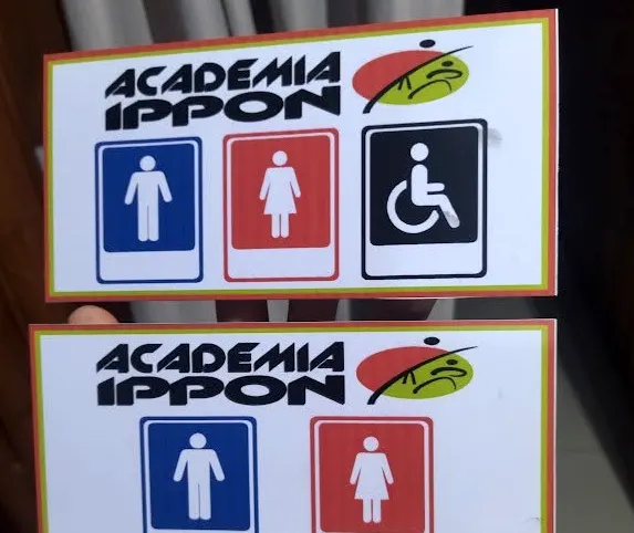 Placas de sinalização de banheiro da Academia Ippon, com pictogramas masculino, feminino e acessível